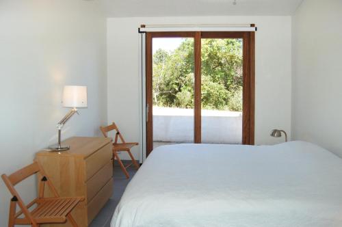 une chambre avec un lit, un bureau et une fenêtre dans l'établissement Villa Coucou Les Amis, à Sainte-Lucie de Porto-Vecchio