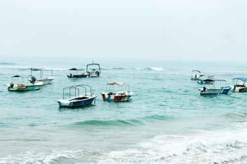 a group of boats floating in the ocean at Coral Seas Beach Hikkaduwa in Hikkaduwa