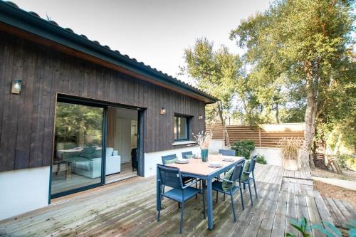 une terrasse en bois avec une table et des chaises. dans l'établissement La Dépendance Canopée du Lac, à Seignosse