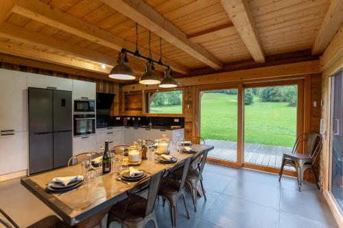 una cucina con un grande tavolo e sedie in legno di Le Chalet de Bequi a Bellefontaine