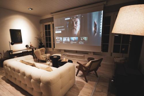 a living room with a white couch and a large screen at Olive Hill Spa, Views & Home Cinema in Kanimbla