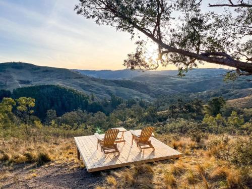 two chairs sitting on a wooden table on top of a hill at Olive Hill Spa, Views & Home Cinema in Kanimbla
