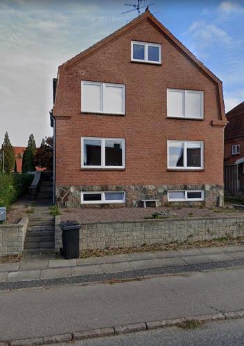 a brick house with white windows on a street at The Hidden Sea View in Sønderborg