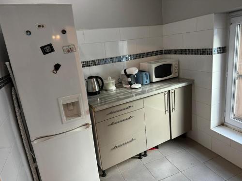une petite cuisine avec un réfrigérateur et un micro-ondes dans l'établissement Quiet self-catering apartment, à Aubervilliers