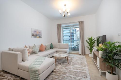 a white living room with a couch and a tv at Free housekeeping visits during your stay - StayShort - Comfy 1-Bedroom Apartment Perfect for 4 in JLT in Dubai