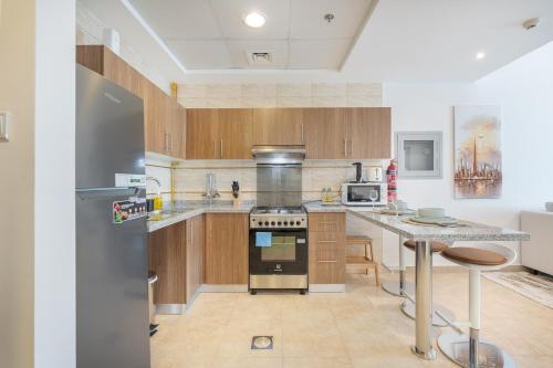 a kitchen with wooden cabinets and a stainless steel refrigerator at Free housekeeping visits during your stay - StayShort - Comfy 1-Bedroom Apartment Perfect for 4 in JLT in Dubai