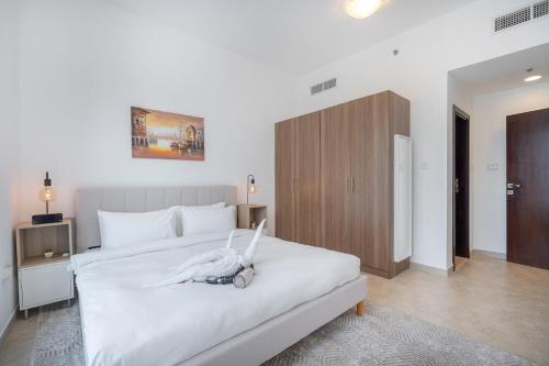a bedroom with a white bed and a wooden cabinet at Free housekeeping visits during your stay - StayShort - Comfy 1-Bedroom Apartment Perfect for 4 in JLT in Dubai