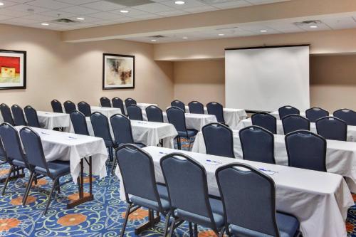 a conference room with tables and chairs and a screen at Holiday Inn Express & Suites Detroit - Novi by IHG in Novi