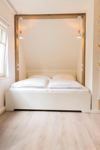 a white bed in a room with a wooden floor at Hus Mattgoot - Doppelzimmer No.2 in Böhl