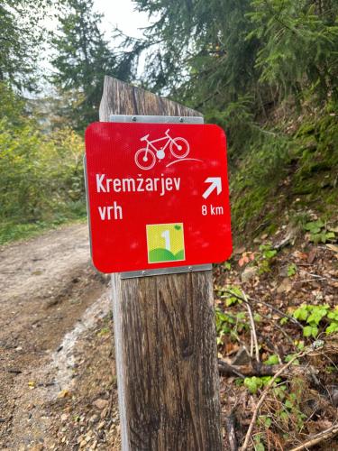 a red sign on a wooden post on a bike trail at Apartments Barbra - Robinson life in Slovenj Gradec