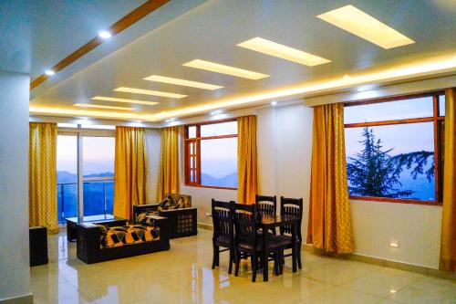 a living room with a table and chairs and windows at Deodar dreams family apartment in Mashobra