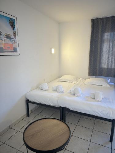 Cette chambre comprend un lit avec des draps blancs et une table. dans l'établissement Résidence Graziella Studio 324, à Juan-les-Pins