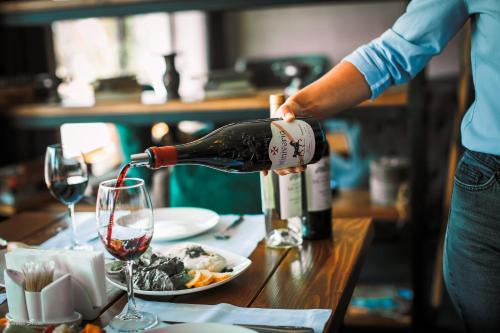 a person pouring wine into a plate of food at Alpine Lounge Boutique Hotel in Stepantsminda