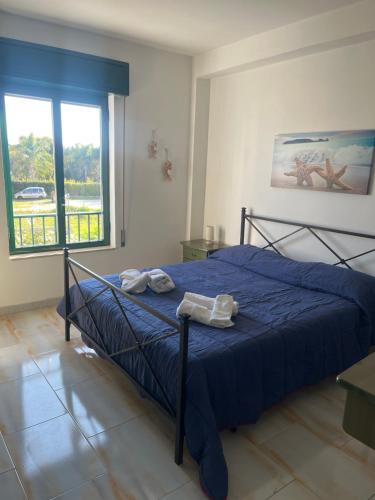 una camera da letto con un letto con lenzuola blu e una finestra di La casetta a Marzamemi