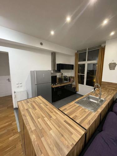 Il comprend une cuisine équipée d'un comptoir en bois et d'un réfrigérateur. dans l'établissement Appart 7 personnes centre-ville, à Lille