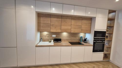 une cuisine avec des armoires blanches et un évier dans l'établissement L 'Écrin Cosy with Private Terrace, à Brétigny-sur-Orge