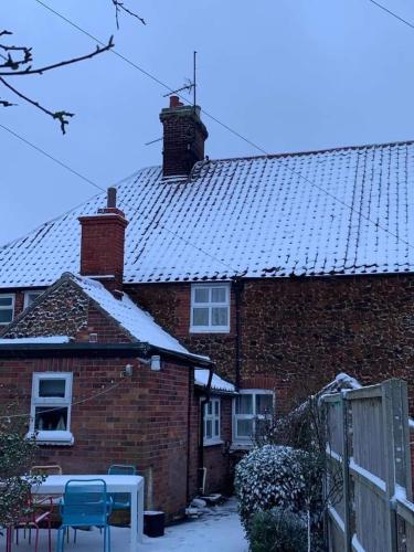 a red brick house with snow on the roof at Pollywiggle Cottage, Dog Friendly cottage in Heacham in Heacham