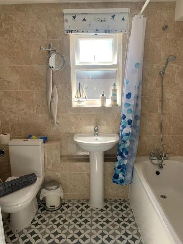 a bathroom with a sink and a toilet and a tub at Pollywiggle Cottage, Dog Friendly cottage in Heacham in Heacham