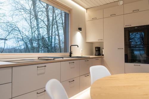 une cuisine avec des armoires blanches, une table et une fenêtre dans l'établissement Citymökki kaupungissa Joensuu, à Joensuu