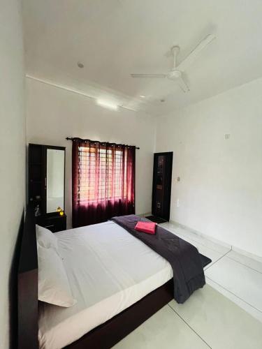 Un dormitorio con una gran cama blanca con ventana. en aphrodite home stay, en Pinangode