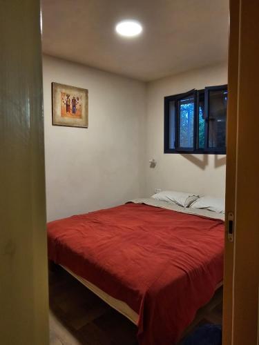 a bedroom with a bed with a red blanket at Housing unit in Emek Yazraal in Hanaton