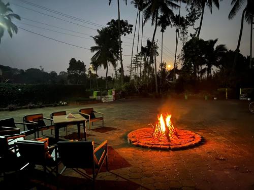 a fire pit with chairs and a table in front of it at Imara - Crafting Memories in Gonikoppal