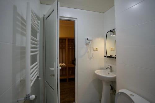 a white bathroom with a sink and a toilet at Hotel Mogzauri in Tbilisi City