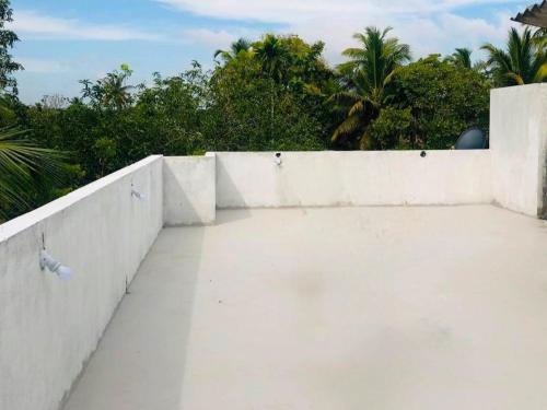a white concrete wall with trees in the background at Zeleny Retreat Home Stay in Matara