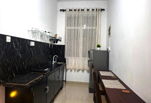 a kitchen with black counters and a sink and a window at Zeleny Retreat Home Stay in Matara