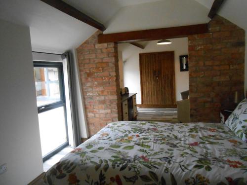 a bedroom with a bed and a brick wall at Callwood Farm Annex Guest Rooms in Belper