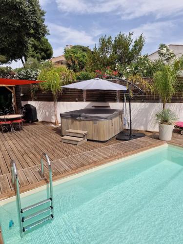 une piscine avec une table et un parasol dans l'établissement Maison avec SPA et PISCINE 2 chambres, à Ajaccio