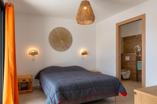 ein Schlafzimmer mit einem Bett mit einer blauen Bettdecke in der Unterkunft Les Villas de la Résidence U Veniqui in Favone
