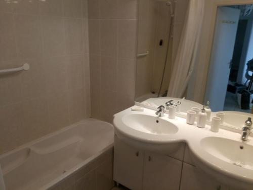 La salle de bains est pourvue d'un lavabo, d'une baignoire, d'un lavabo et d'un miroir. dans l'établissement Les pieds dans l'eau salée, à Biscarrosse