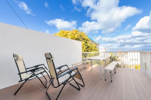 a balcony with two chairs and a table on a deck at Shirahama White Beach House - Self Check-In Only in Shirahama