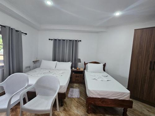 a bedroom with two beds and a table and chairs at JP Self Catering in Mahe