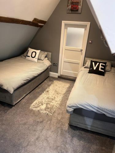 a attic bedroom with two beds and a door at No1 Townhouse - Luxury Spacious 2 bedroom townhouse, central location in Lincolnshire