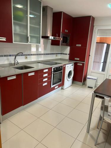 a kitchen with red cabinets and a washing machine at Piso El almendro Lerma in Lerma