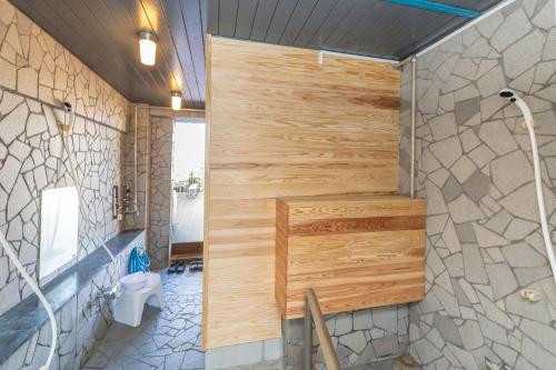a bathroom with a toilet and a wooden wall at Shirahama White Beach House - Self Check-In Only in Shirahama