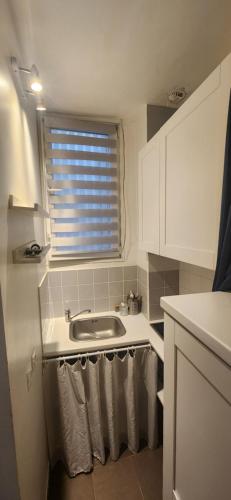 d'une cuisine avec évier et d'une fenêtre avec serviettes. dans l'établissement Studio 103 Bail mobilité - Appartement pour voyages d'affaires et d'études, à Paris