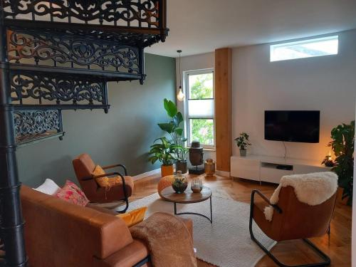 a living room with a couch and chairs and a tv at Luxurious house close to the center of Amsterdam in Oostzaan