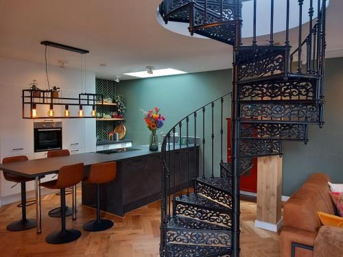 a spiral staircase in a living room with a table and a kitchen at Luxurious house close to the center of Amsterdam in Oostzaan