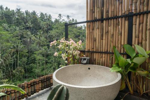 a bath tub sitting next to a fence with flowers at Legong Sebatu Villa in Ubud