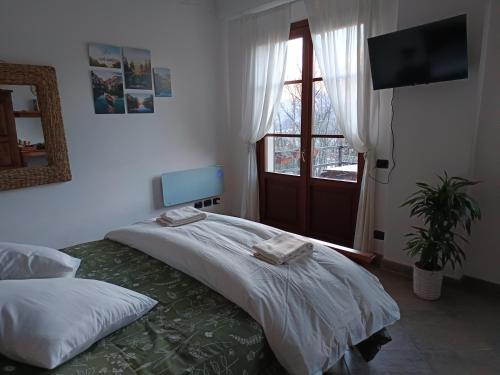 a bedroom with a bed and a tv and a window at 2 double rooms apartment- La Casa di Alice in Valbrona