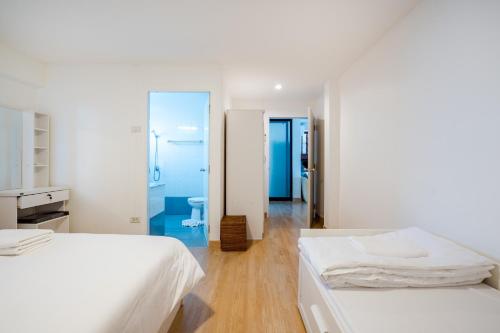 a white bedroom with two beds and a bathroom at ON THE BEACH Beach Front in Ban Tha Sai