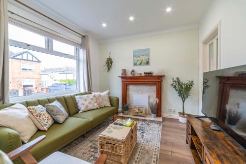 a living room with a green couch and a fireplace at Beautiful Three Bedroom House - Manchester Escape in Manchester