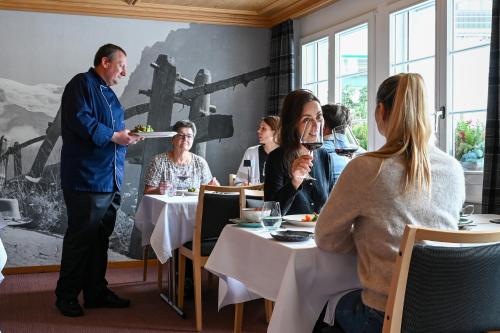 a man holding a plate of food in a restaurant at Hotel St. Josefshaus Engelberg in Engelberg