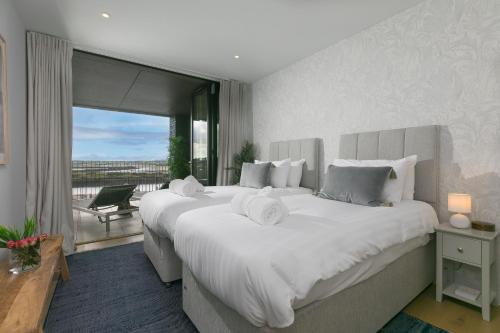 a bedroom with two large white beds and a balcony at 14 An Garth in Hayle