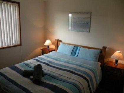 a teddy bear laying on a bed in a bedroom at Waves & Wildlife Cottages Kangaroo Island in Stokes Bay