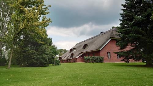 a red brick building with a gambrel roof at De Leev - Landhaus Lübbertsfehn in Ihlow