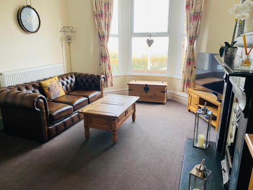 a living room with a leather couch and a coffee table at Ocean Terrace, Ilfracombe, 4 bedrooms, Sleeps 8, Stunning Sea Views, Parking, Garden, Pet Friendly in Ilfracombe